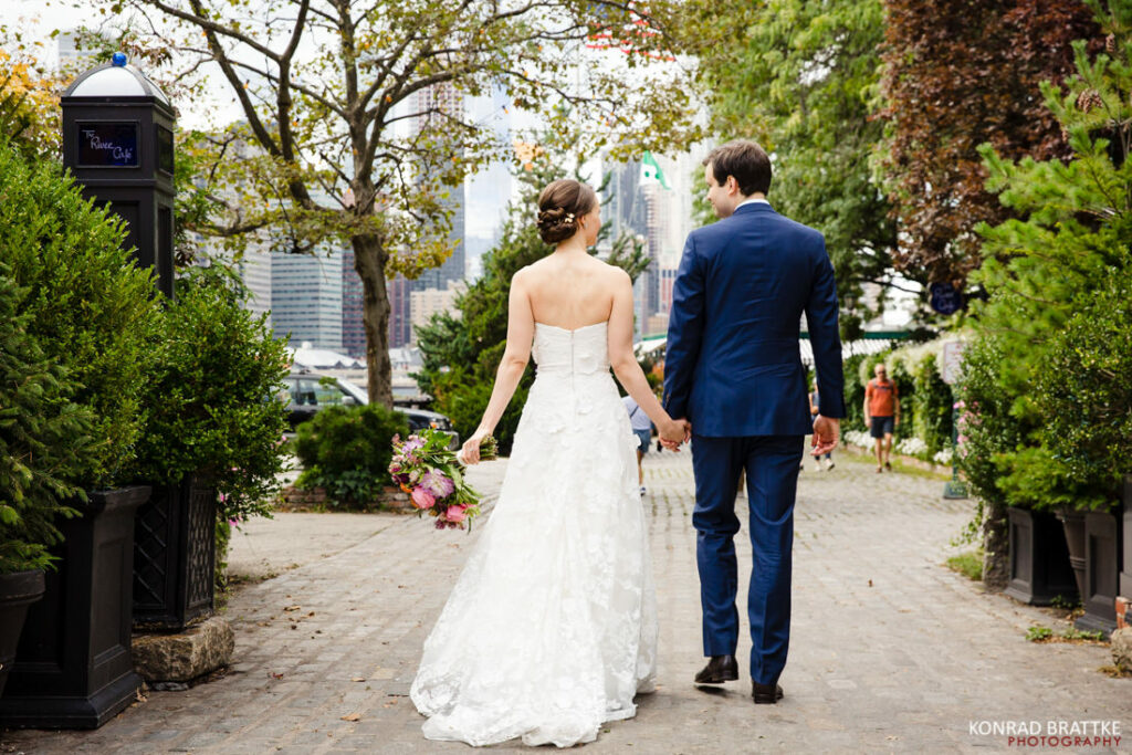 A bride and groom walking down a brick walkway at the River Cafe.