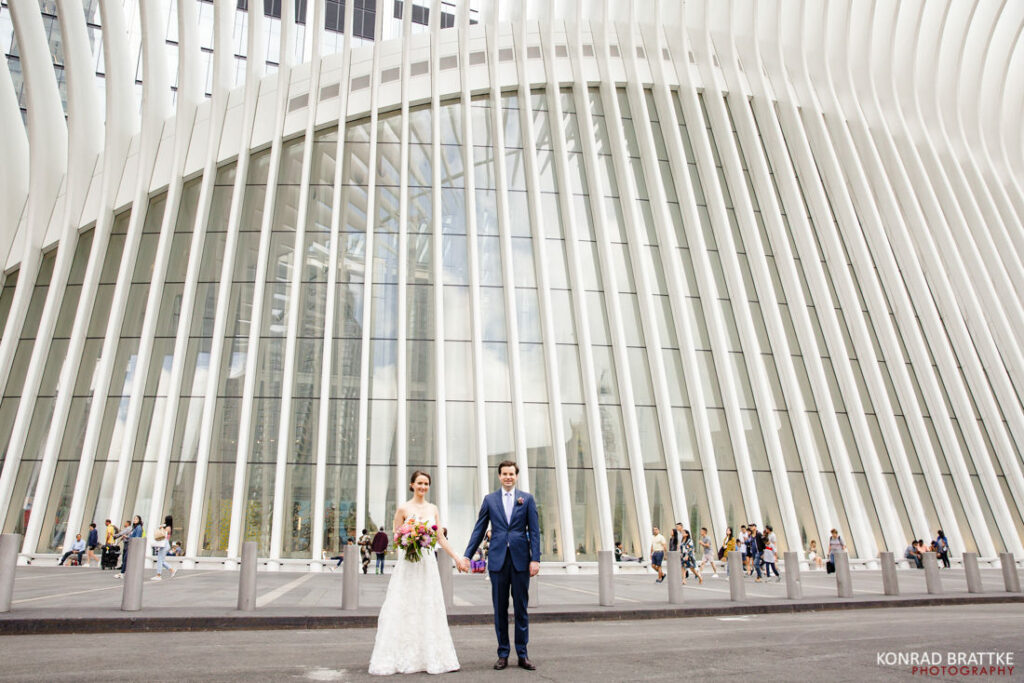 A bride and groom standing in front of the world trade center during their wedding.