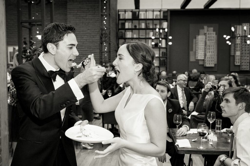 A bride and groom feeding each other cake at a wedding.