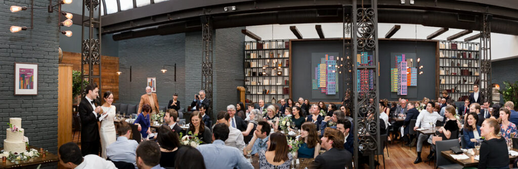 A wedding reception in a large room with a lot of people at The Milling Room.