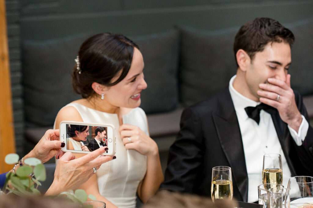 A bride and groom taking a picture with their phone.