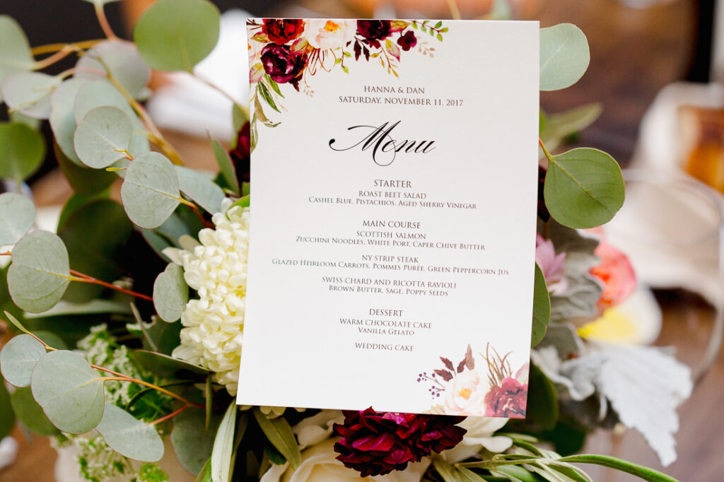 A menu is sitting on a table with flowers and eucalyptus.