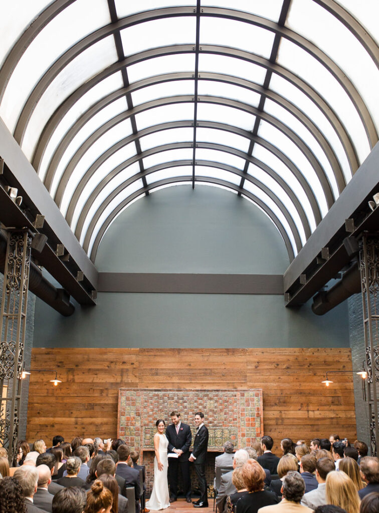 A wedding ceremony is taking place in a large room at The Milling Room in Manhattan.