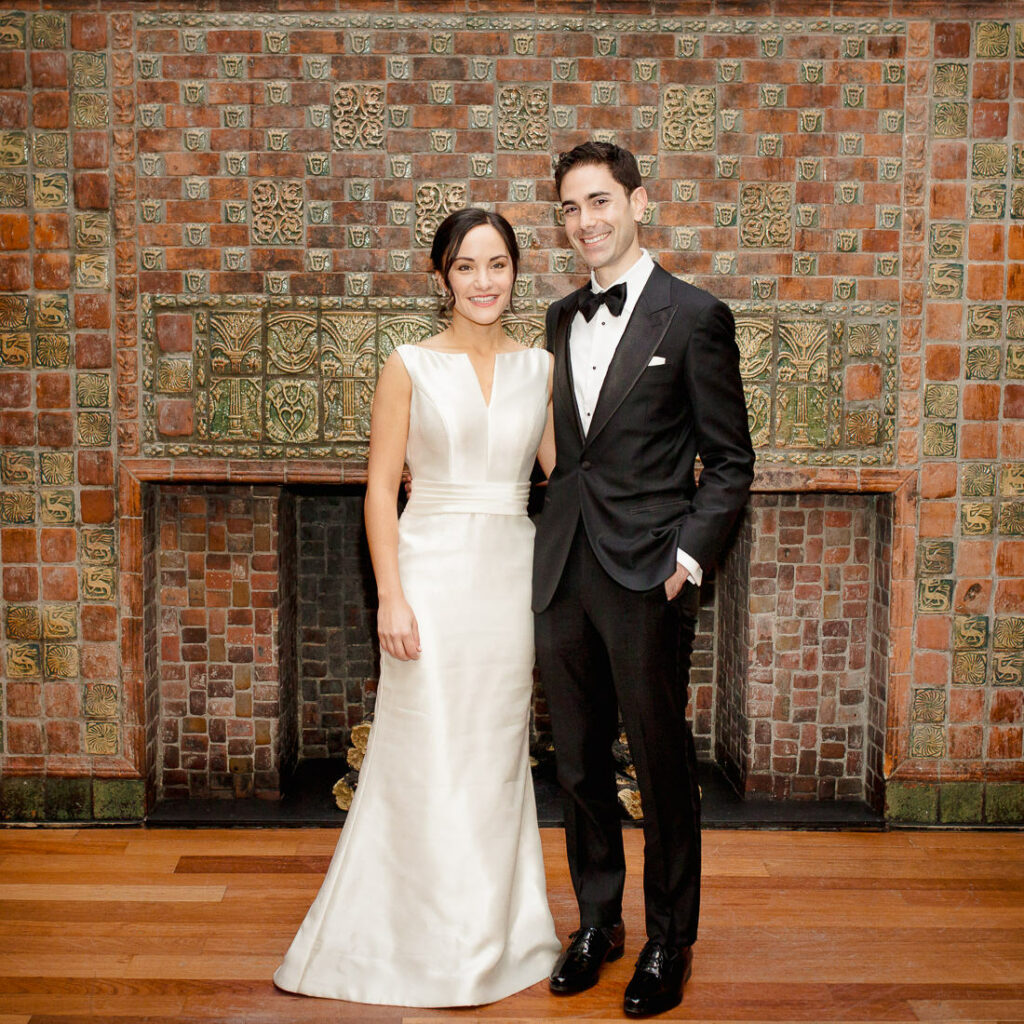 A bride and groom standing in front of a fireplace at The Milling Room.