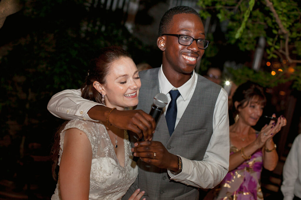 A bride and groom hugging while holding a microphone at Bacchus Bistro.
