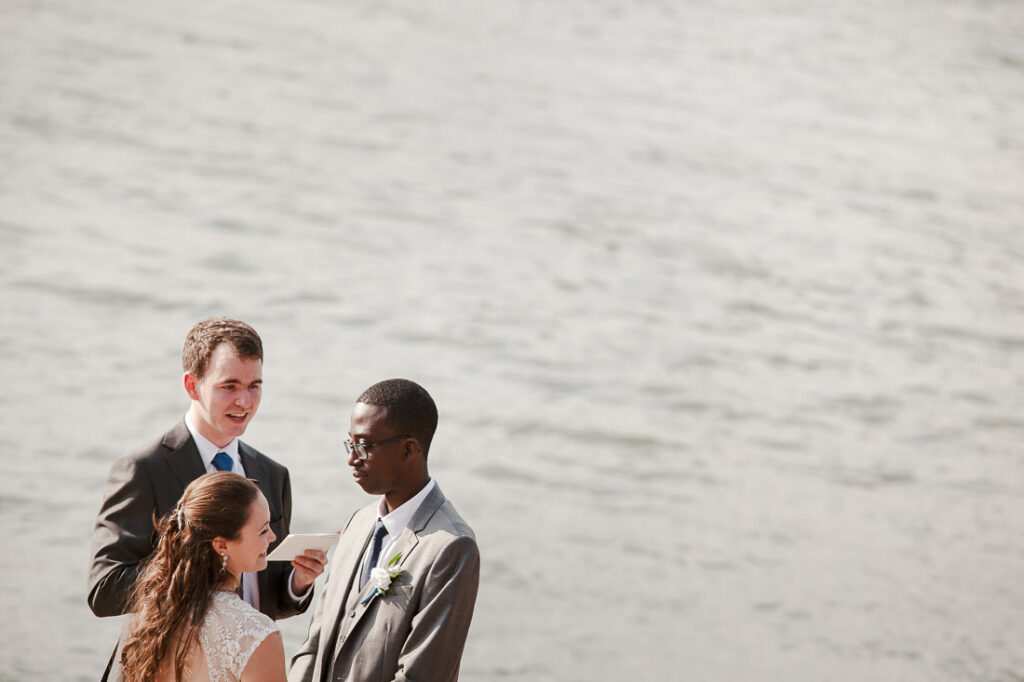 A bride and groom exchange vows in Brooklyn, overlooking a serene body of water.