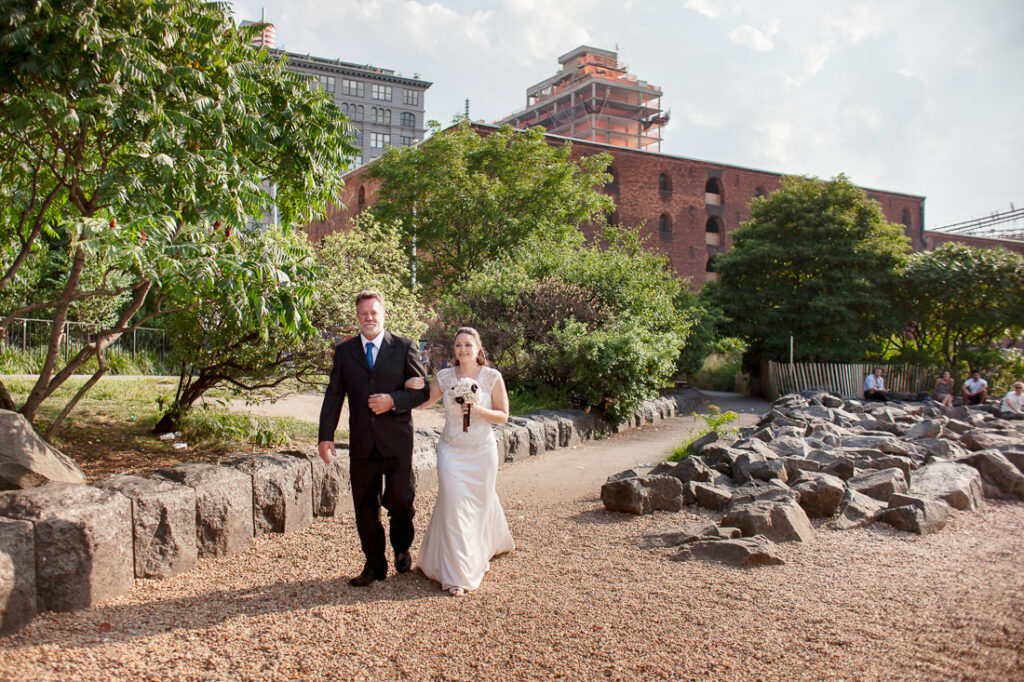 A bride and groom walking down a path with Dumbo in the background.