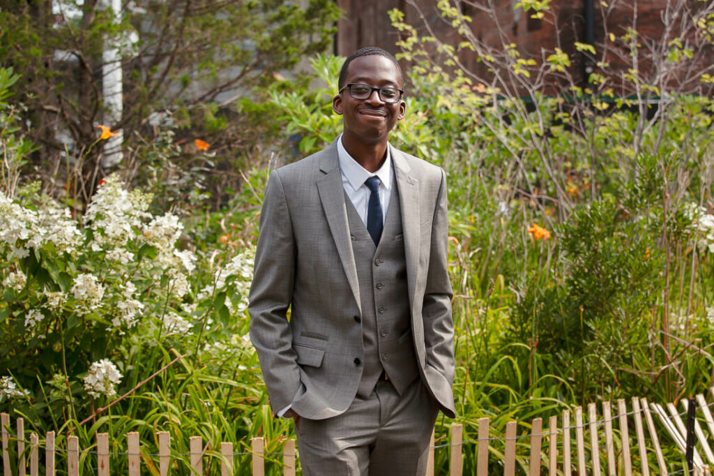 A man in a suit standing in a garden in Dumbo.