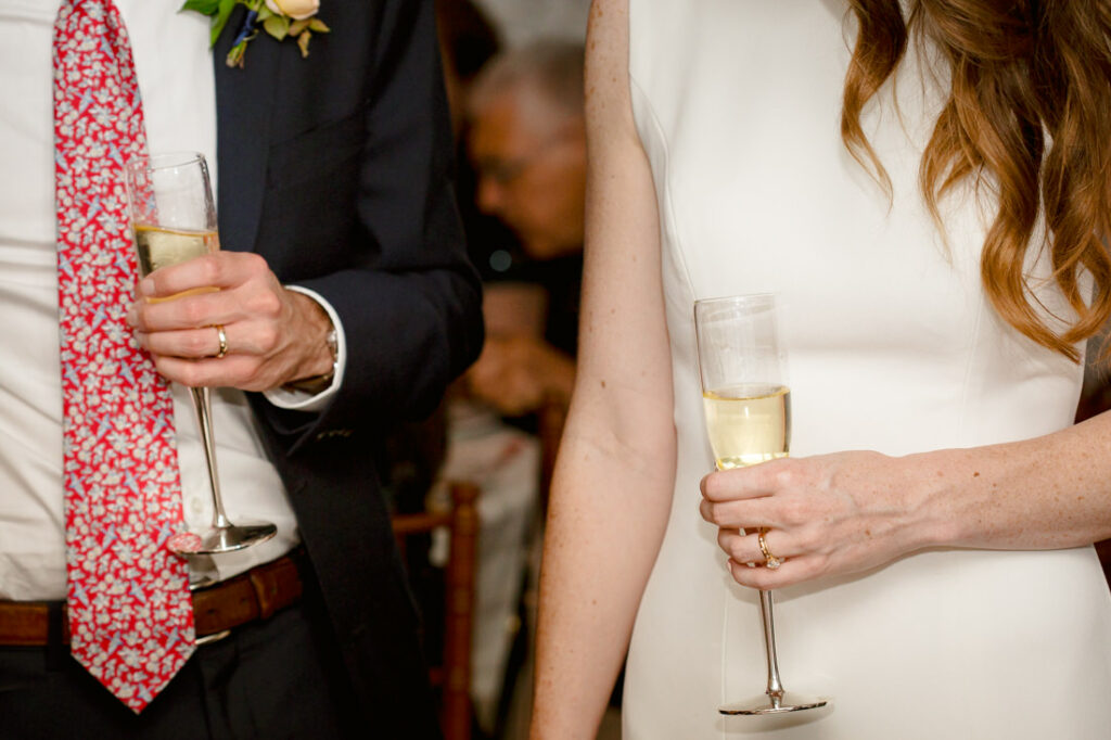 A man and a woman elegantly holding champagne flutes at the New York Botanical Garden.
