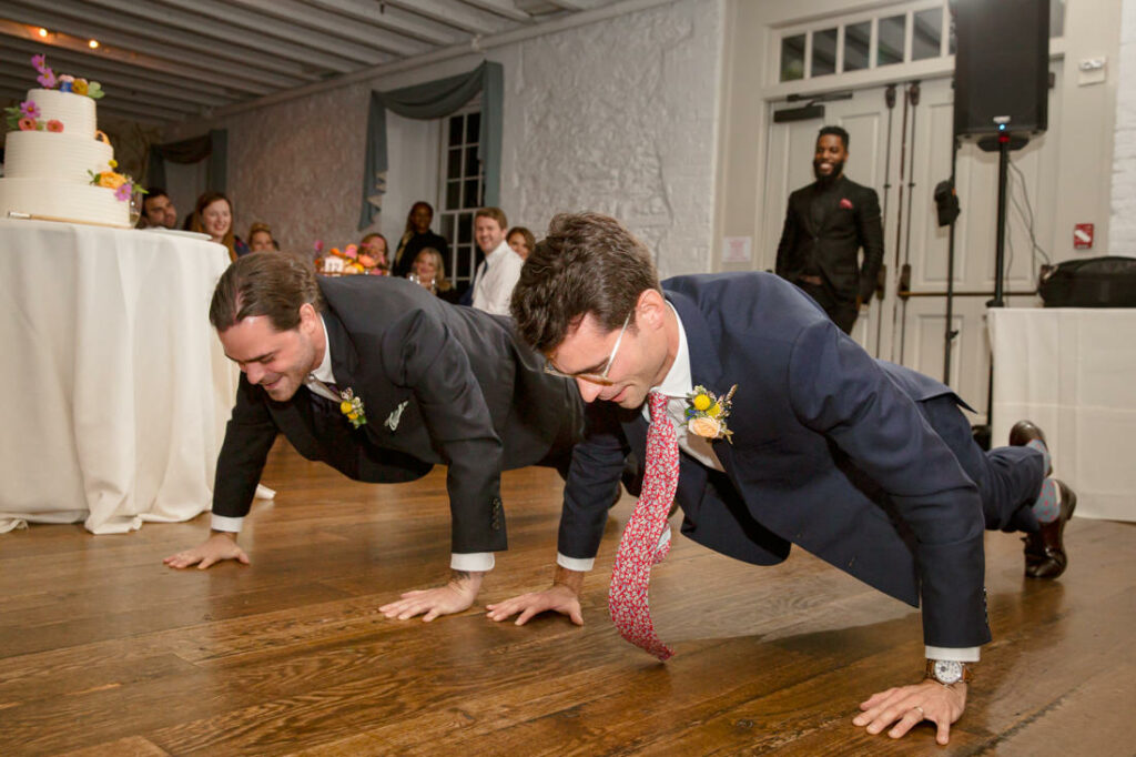 Two men doing push ups on a wooden floor at the New York Botanical Garden.