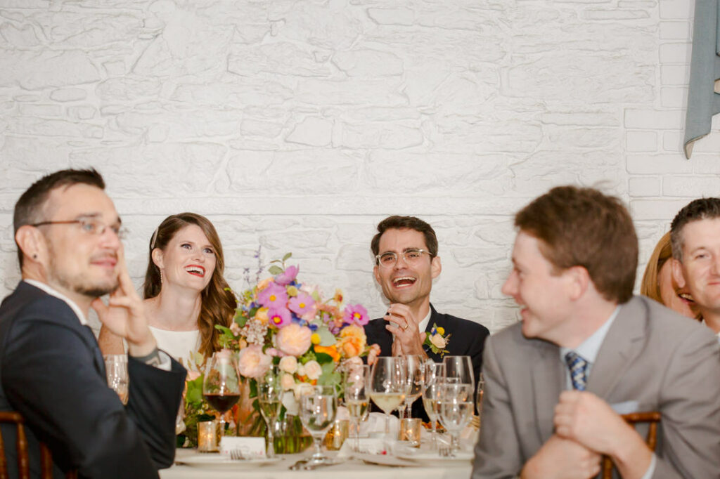 A group of people laughing at a wedding reception held at the New York Botanical Garden.