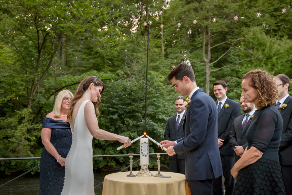 Newlyweds lighting a candle at their wedding ceremony held at the New York Botanical Garden.