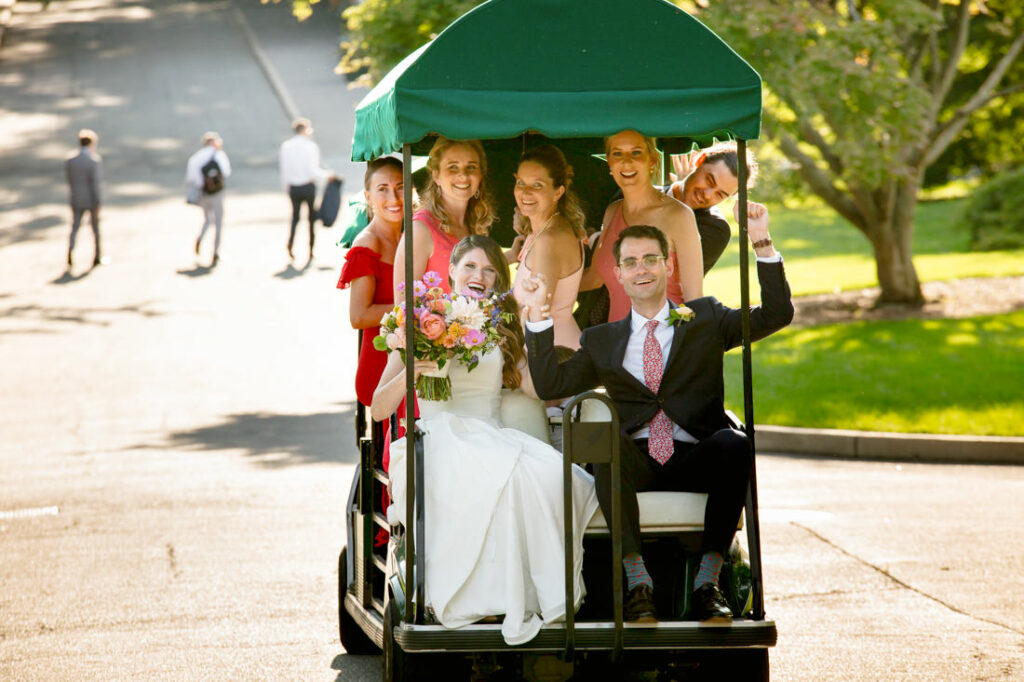 A group of bridesmaids and groomsmen riding in a golf cart at the New York Botanical Garden.