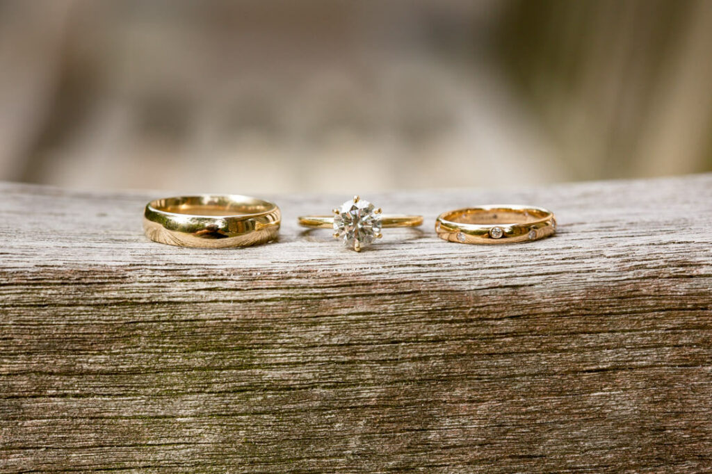 Three gold wedding rings sitting on a wooden table at the New York Botanical Garden.