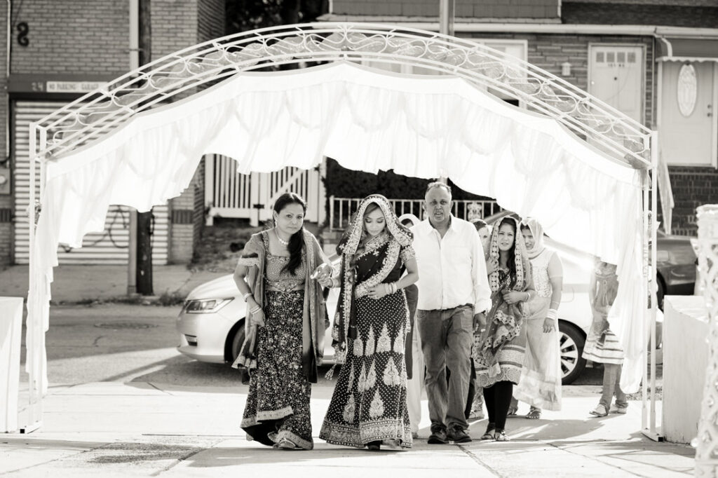 A black and white photo capturing a group of Indian brides and grooms sharing moments of joy during their nikah ceremony.