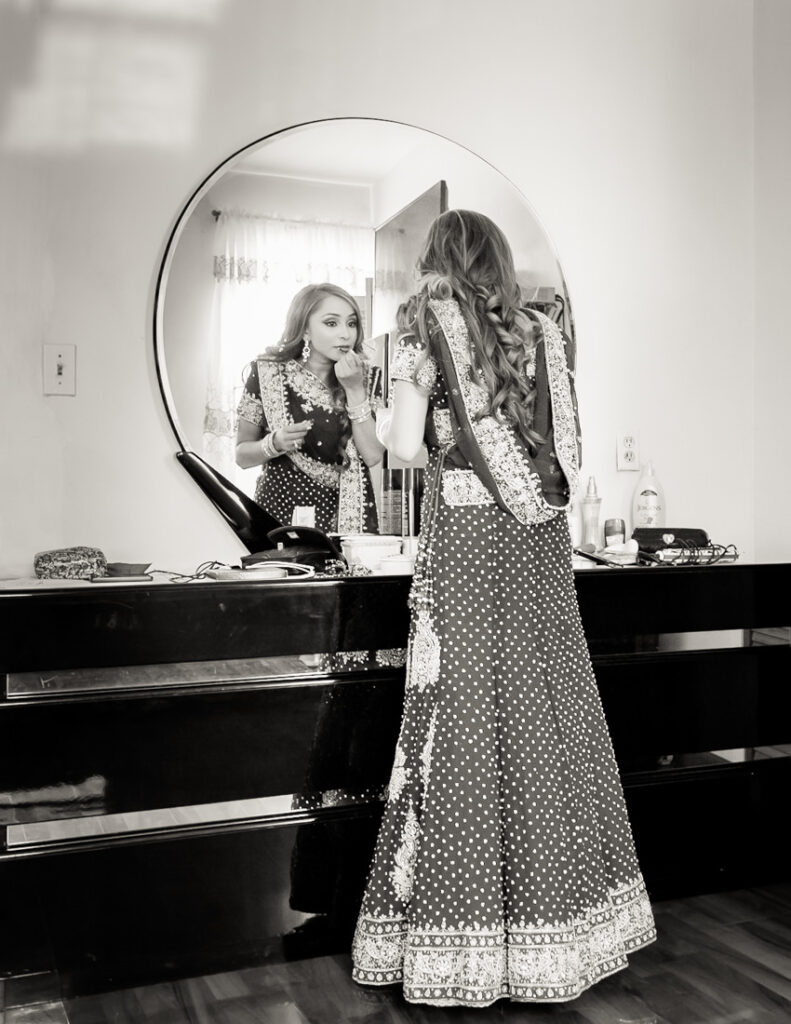 A woman in an Indian dress admiring herself in the mirror.