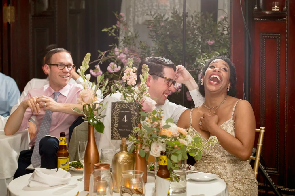 A group of people laughing at a wedding reception at the Montauk Club.
