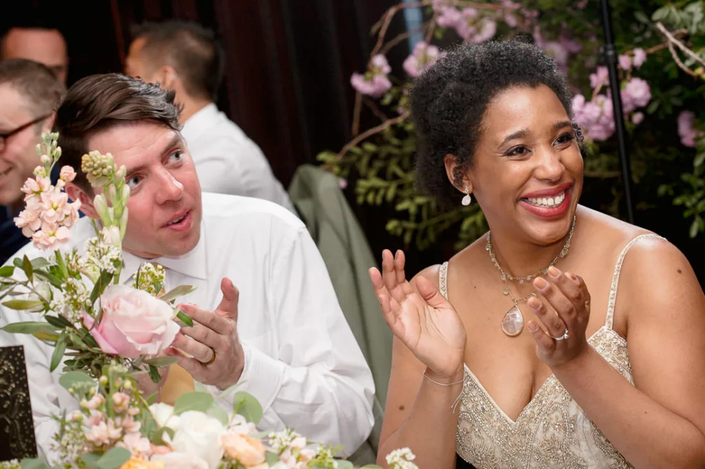 A bride and groom clapping at a wedding reception at the Montauk Club.