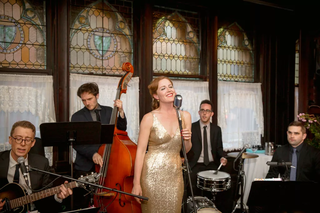 A woman in a gold dress singing with a band at a wedding at the Montauk Club.