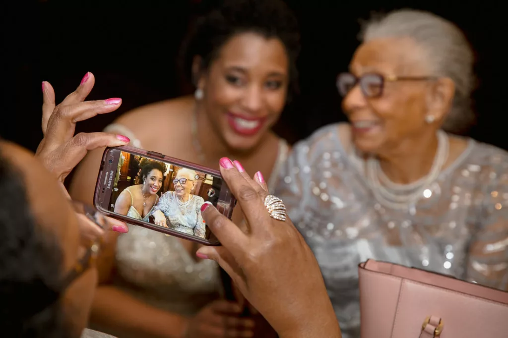 A woman is taking a picture of an older woman with a cell phone.