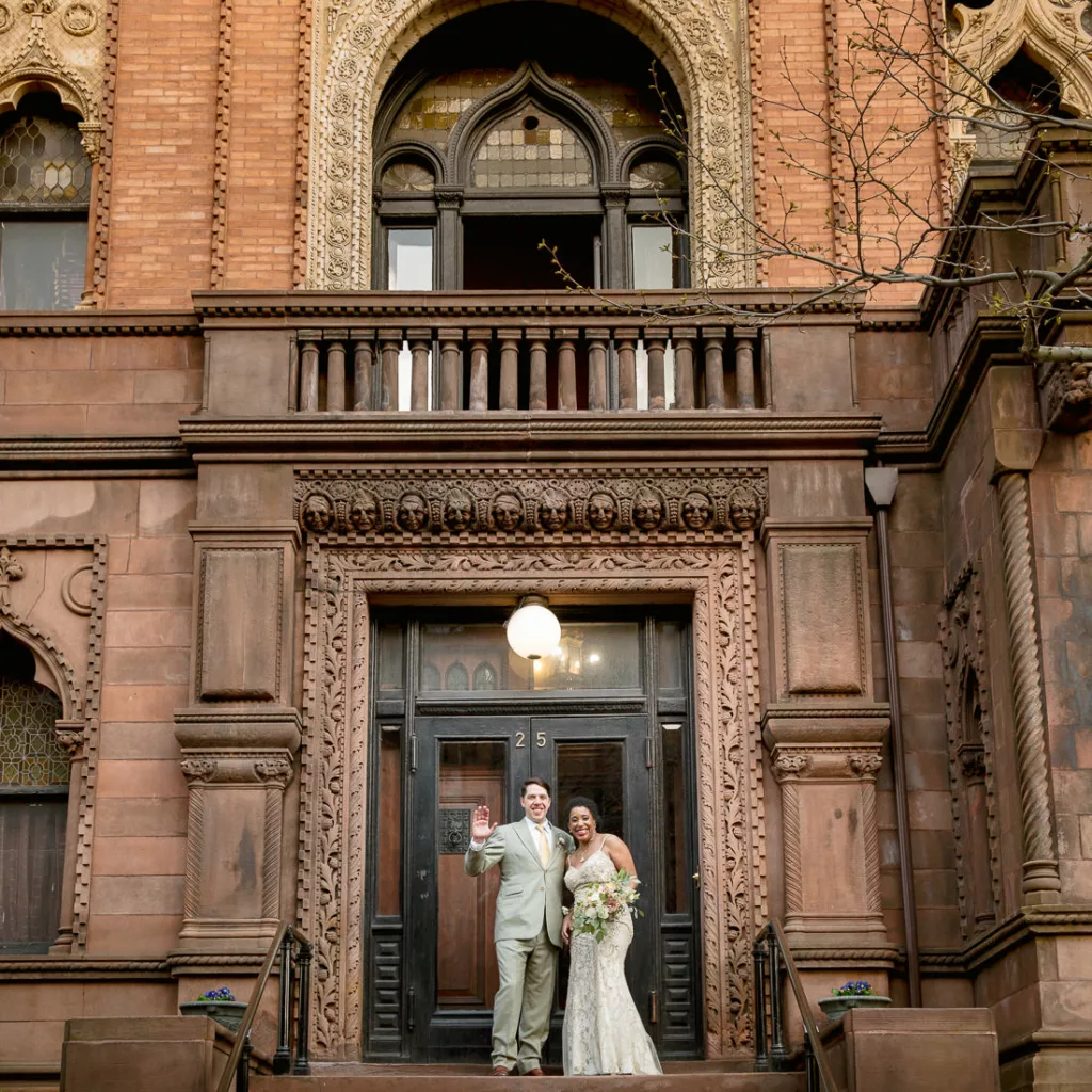 A bride and groom standing on the steps of an ornate building. The Montauk Club in Brooklyn, New York City.