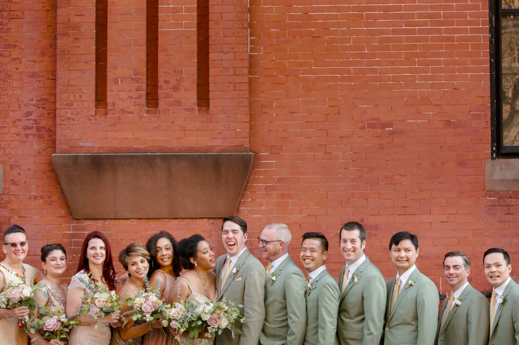 A group of bridesmaids and groomsmen standing in front of a brick building in Park Slope.