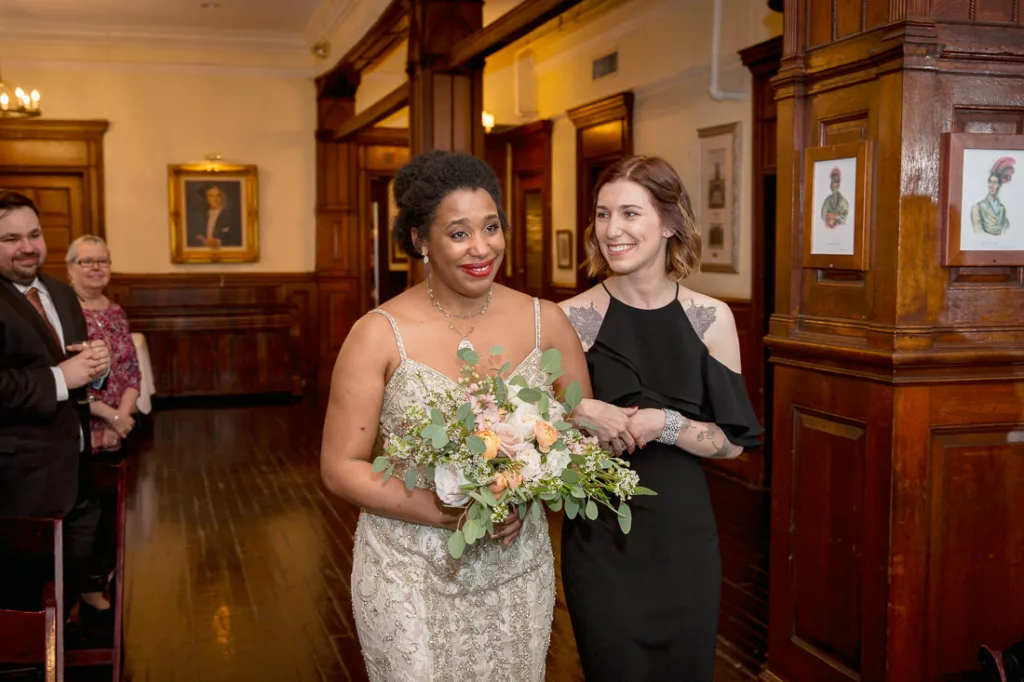 Two women walking down the aisle at a wedding.