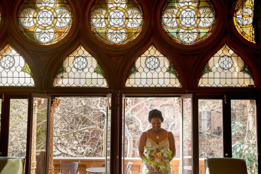 A bride standing in front of a stained glass window at the Montauk Club.