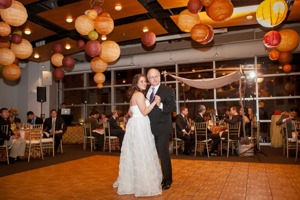 A bride and groom dance in a room with paper lanterns at their venue the VisArts.