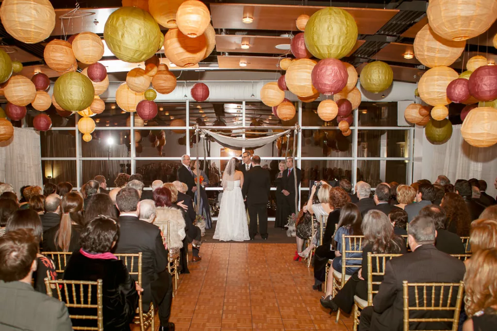 A wedding ceremony with paper lanterns hanging from the ceiling at VisArts in Rockville.