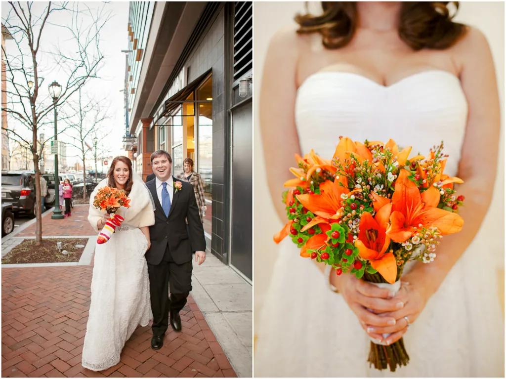 A bride and groom walking down the street with orange flowers.