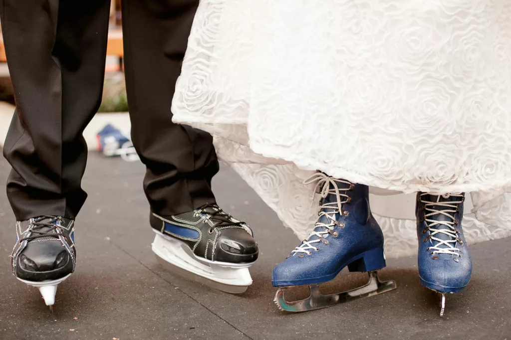 A bride and groom standing on ice skates.
