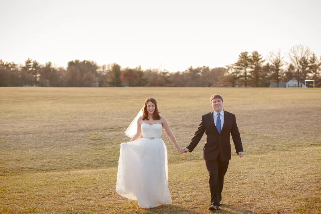 A bride and groom walking through a field at sunset in Rockville, Maryland.