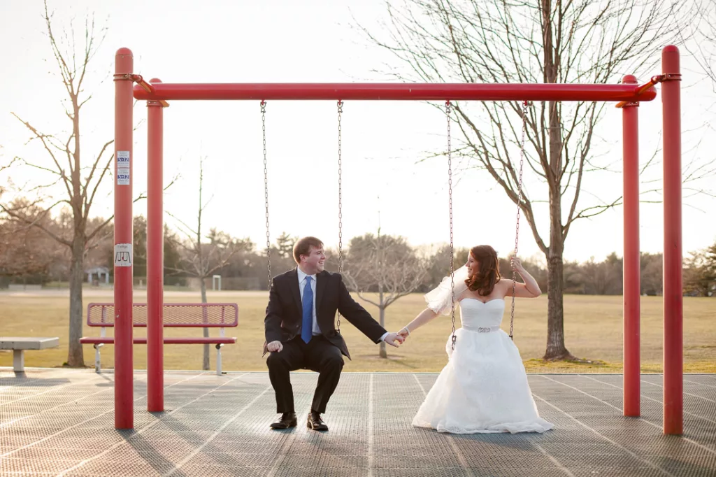 A bride and groom swinging on a red swing.
