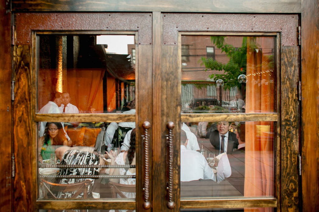 A group of people sitting at tables outside a restaurant adorned with beautiful lights.