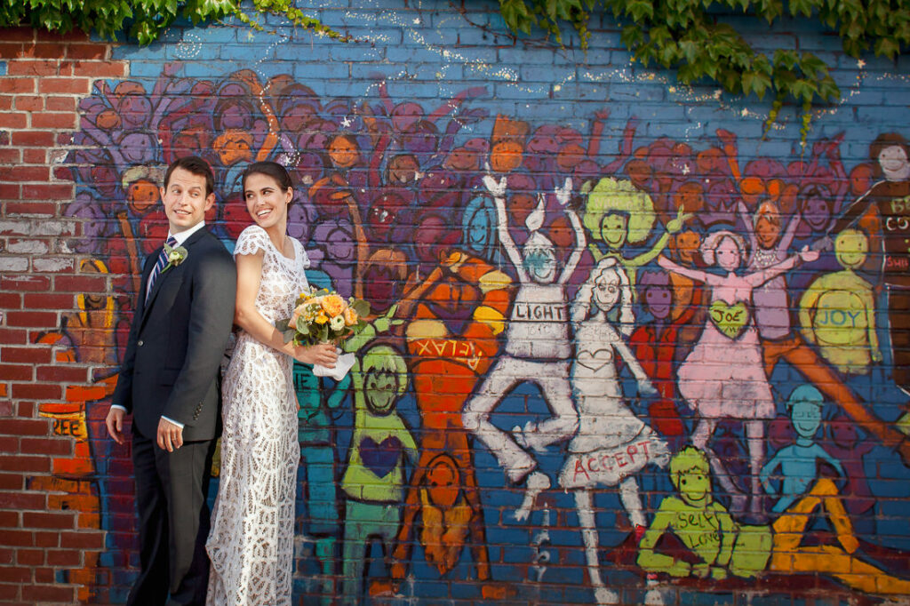 A wedding couple pose in front of a mural in Brooklyn.
