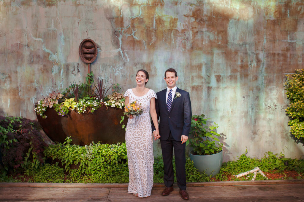 A bride and groom standing in front of a wall at a restaurant in Williamsburg.