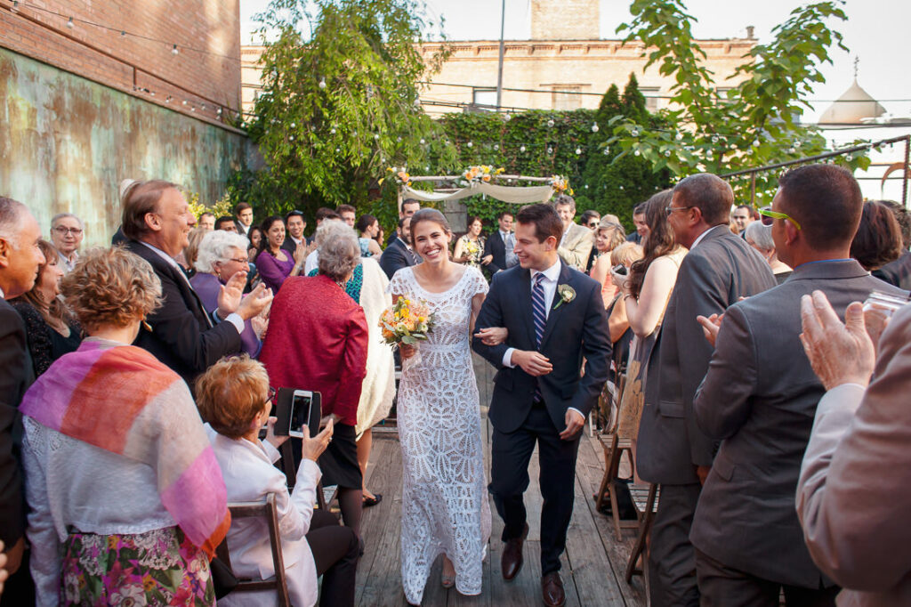 A bride and groom, surrounded by the beauty of nature, walk down the aisle at an outdoor wedding on mymoon.