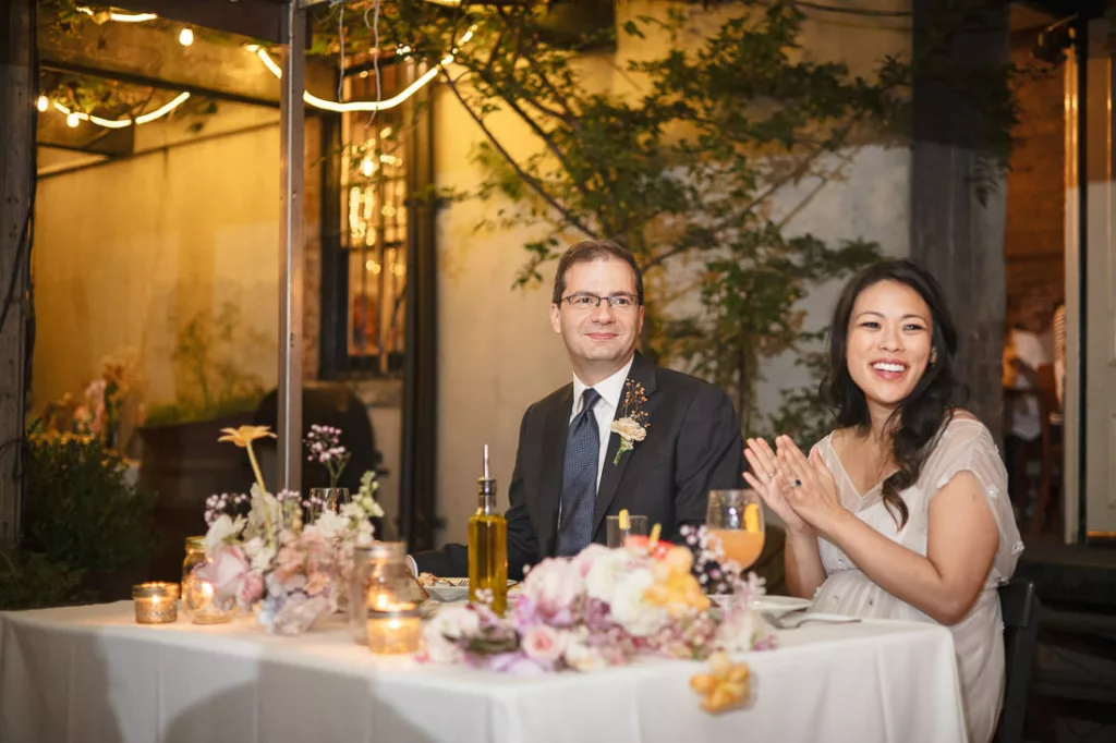 A bride and groom clapping at their wedding reception at Frankies 457 Spuntino.