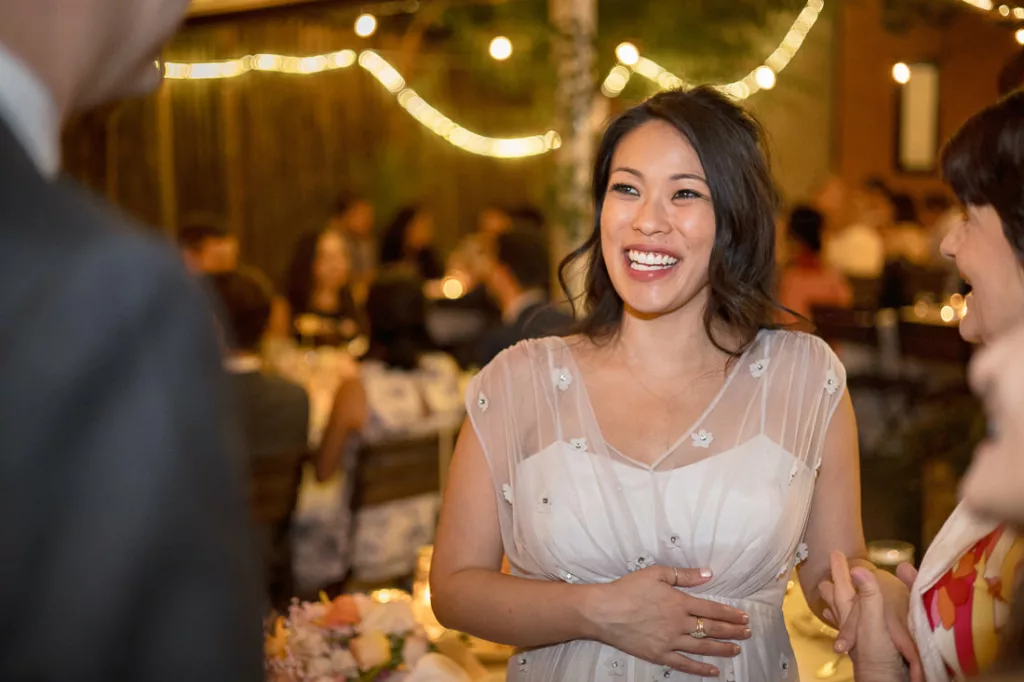 A woman laughing at a wedding reception.