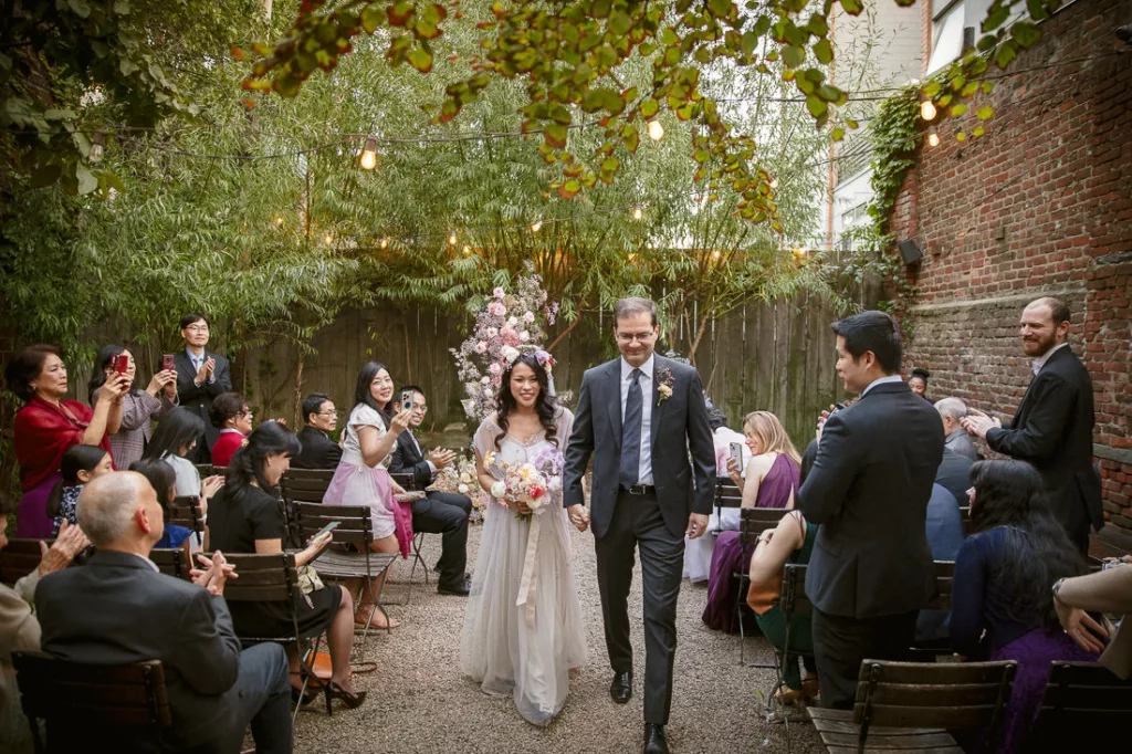 A bride and groom walking down the aisle at an outdoor wedding at Frankies 457 Spuntino.