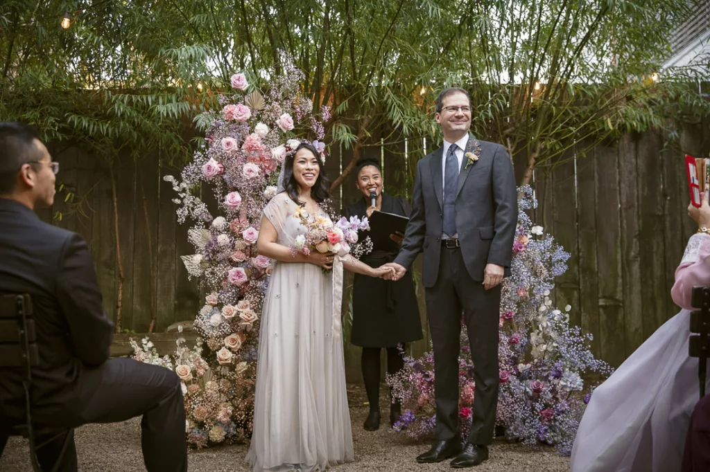 A bride and groom exchange vows in front of a flower garden.