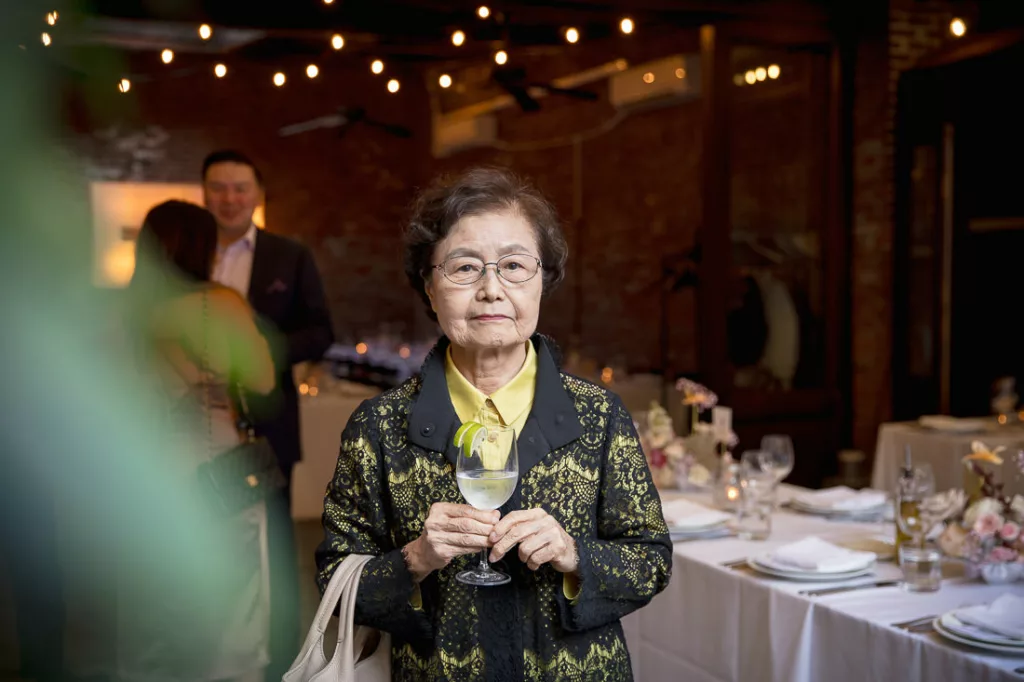 A woman holding a glass of wine in front of a table.