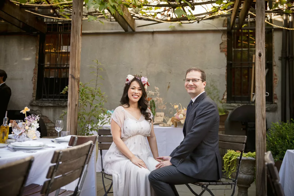 A bride and groom sitting at a table in a courtyard at Frankies 457 Spuntino.