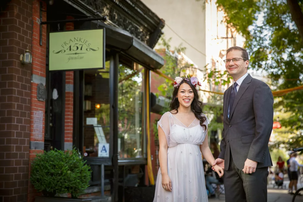 A bride and groom standing in front of Frankies 457 Spuntino on their wedding day.