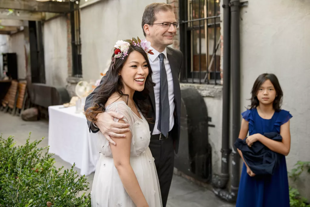 A man in a wedding dress and a girl in a flower crown.