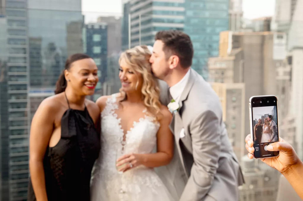 A bride and groom are taking a photo on a rooftop at The Skylark in NYC.