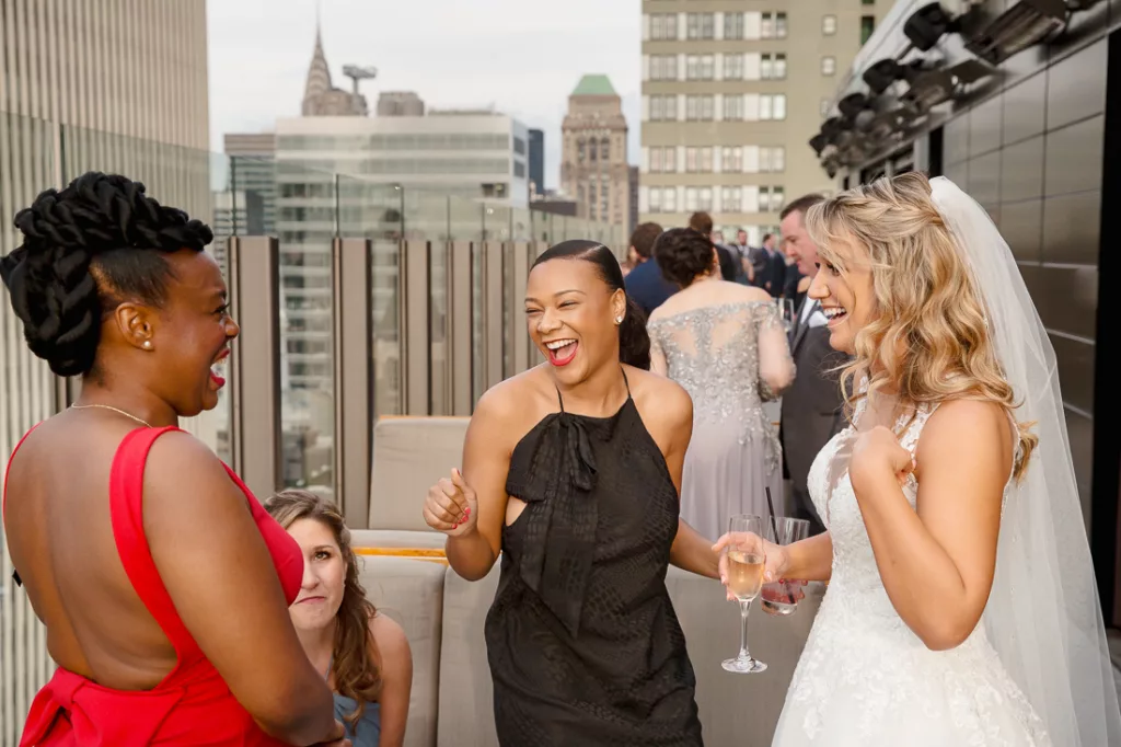 A bride and her bridesmaids laughing on a rooftop at The Skylark in NYC.