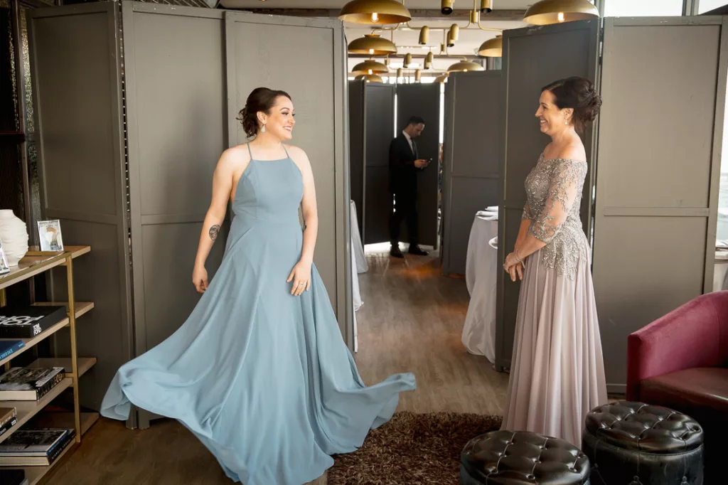Two bridesmaids in blue dresses standing in a room.