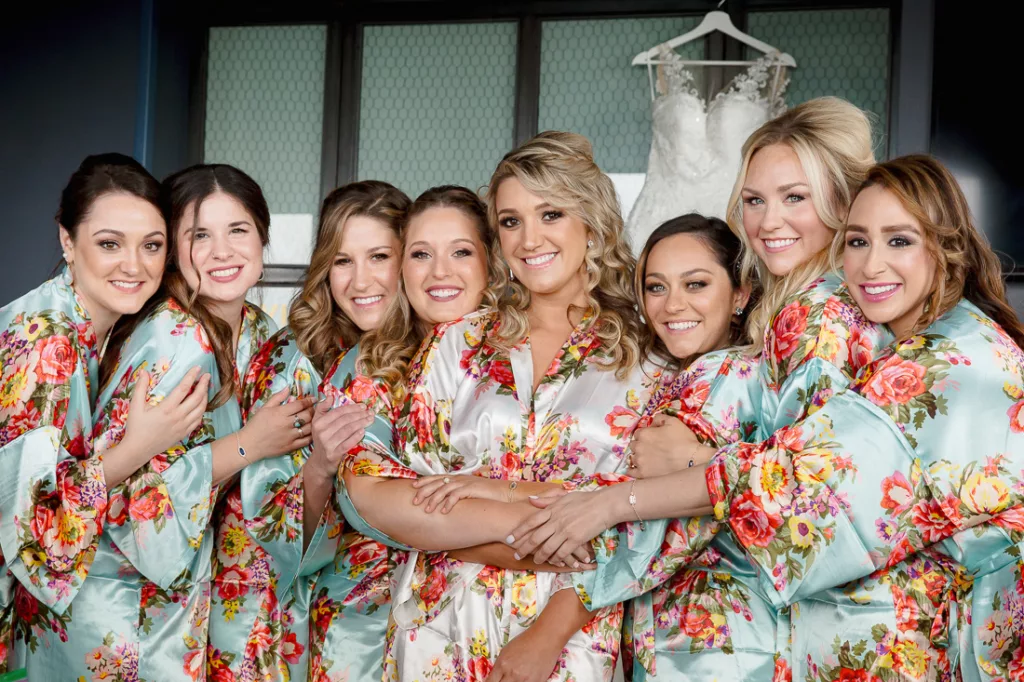 A group of bridesmaids in floral robes posing for a photo.